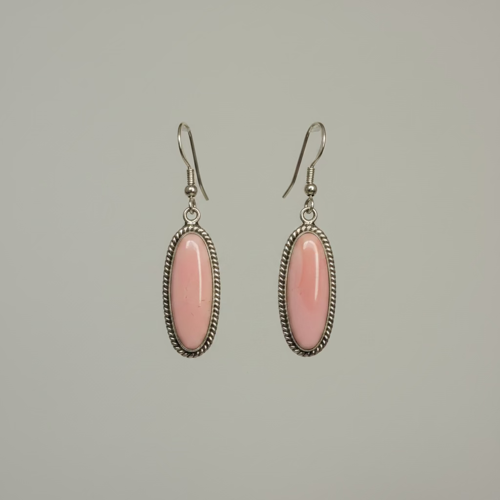Pair of pink oval earrings with silver settings on a gray background